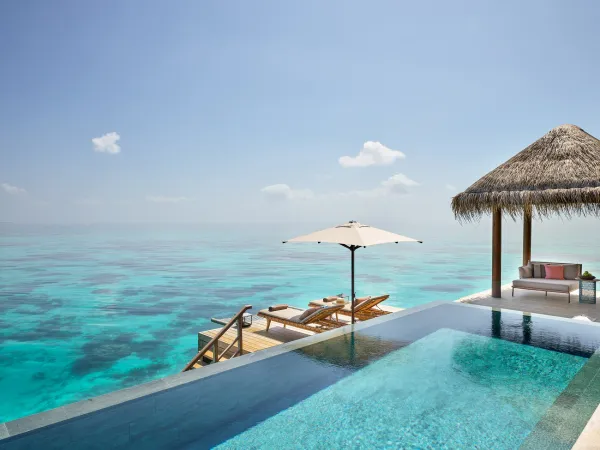 Overwater terrace at JOALI Maldives Three‑Bedroom Ocean Residence, with infinity pool, loungers, umbrella and ocean views
