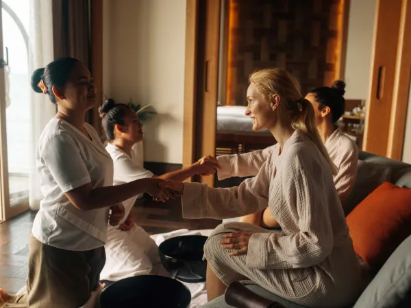 Guest greeted by spa therapist in tranquil JOALI Maldives ESPA treatment lounge.