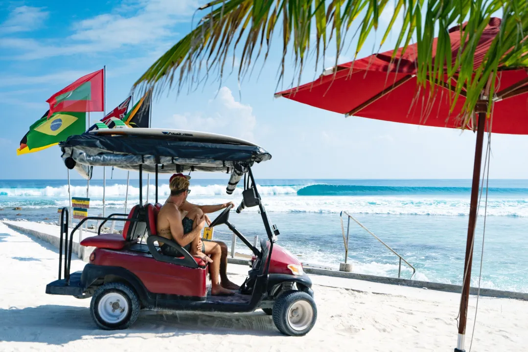Surfer on buggy at Niyama Private Islands Maldives – beachfront scene with surfboard, ocean waves, and island adventure vibes