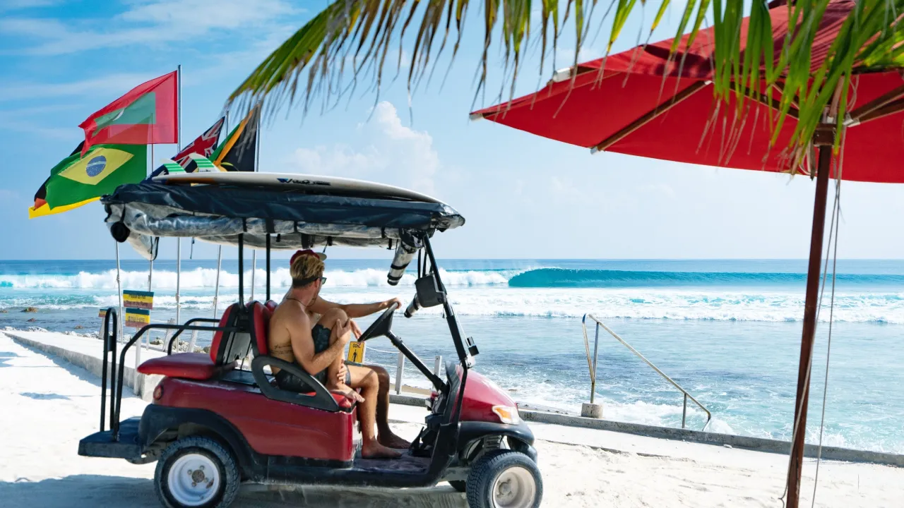 Surfer on buggy at Niyama Private Islands Maldives – beachfront scene with surfboard, ocean waves, and island adventure vibes