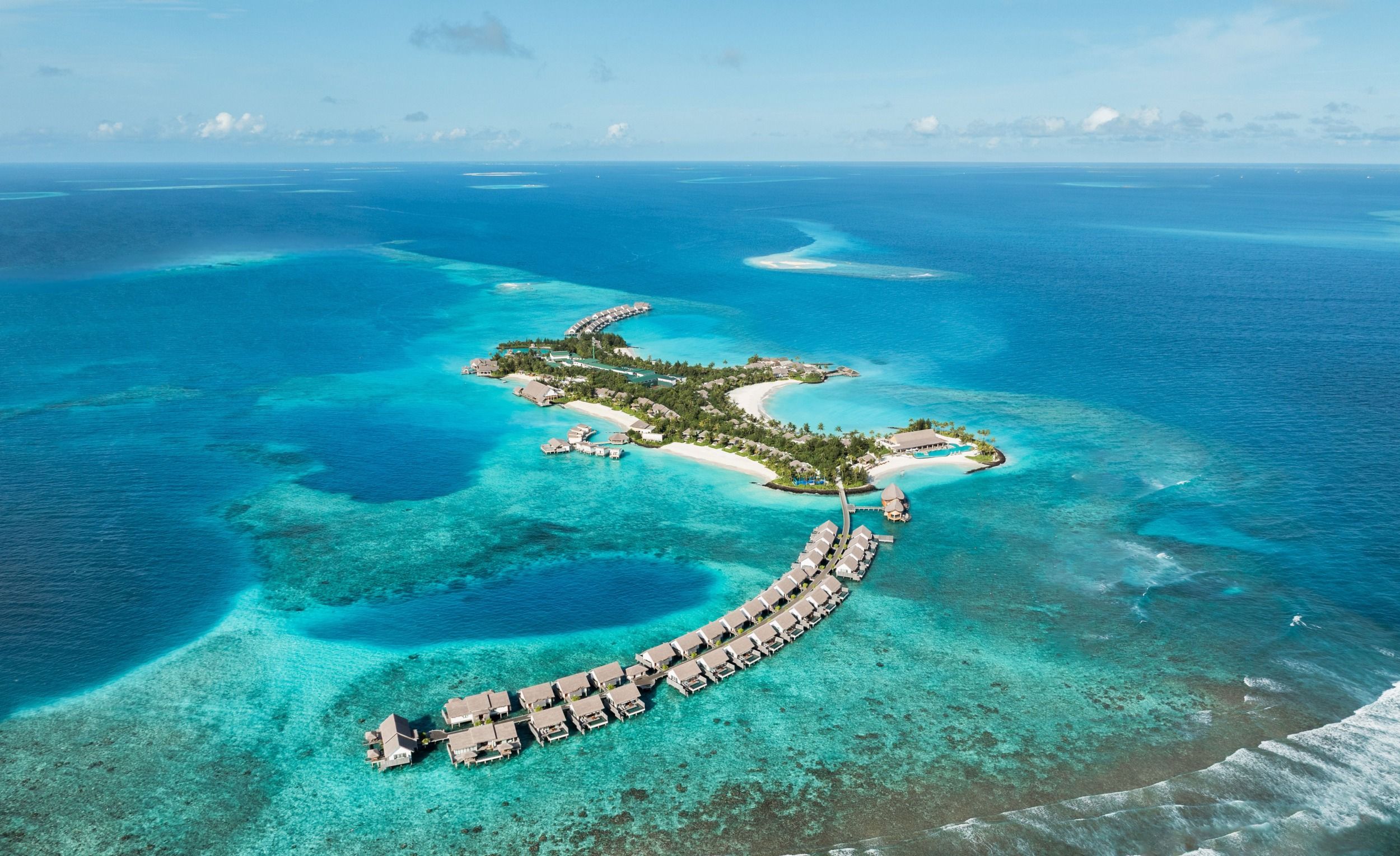 Aerial view of Hilton Maldives Amingiri Resort & Spa with overwater villas, white sand beaches, and turquoise lagoon.